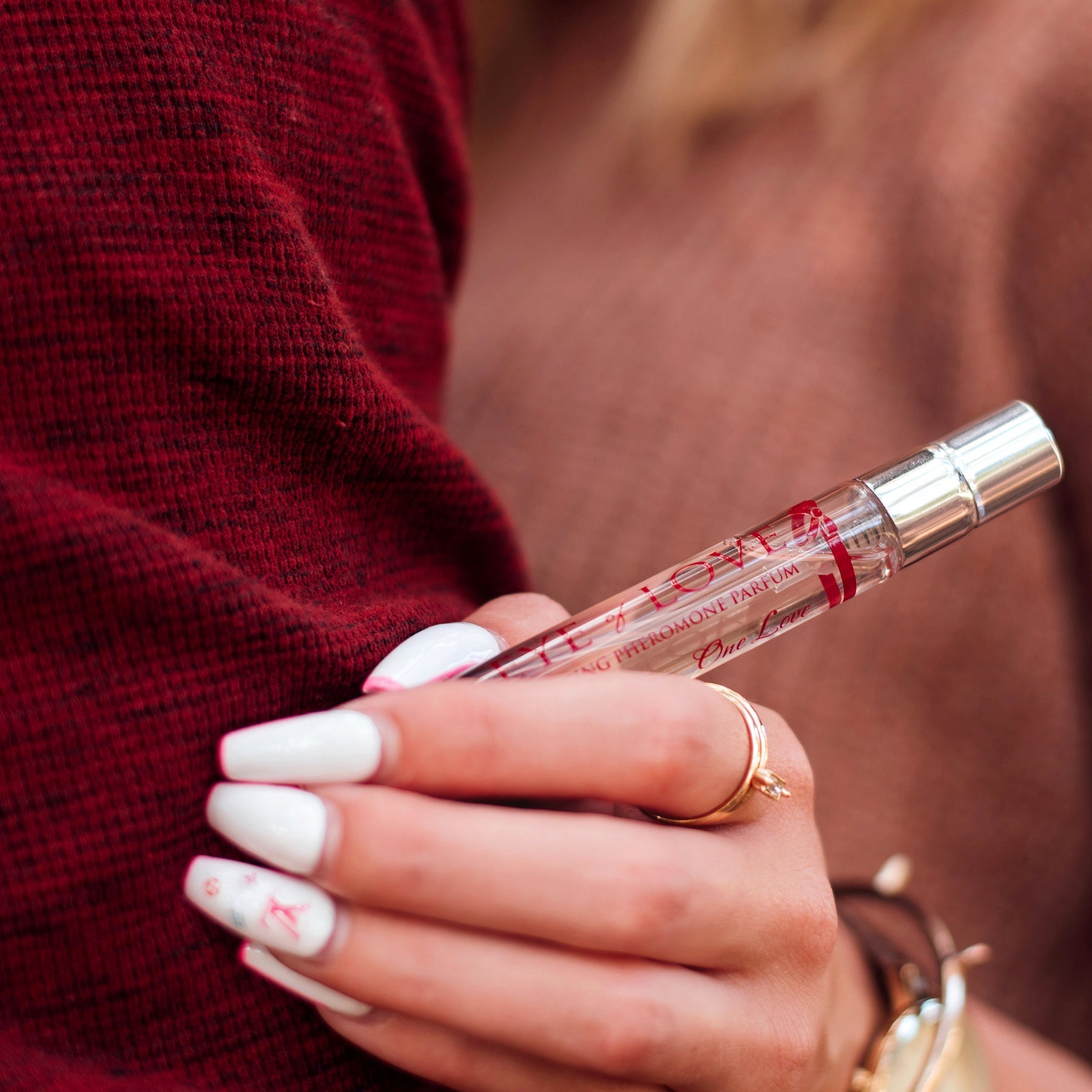 A woman's hand holds a 10ml bottle of One Love Pheromone Perfume.