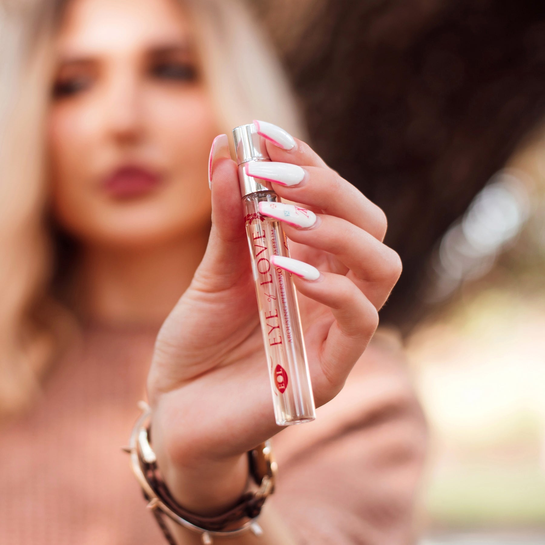 A woman holds a 10ml bottle of Eye of Love Pheromone Perfume.