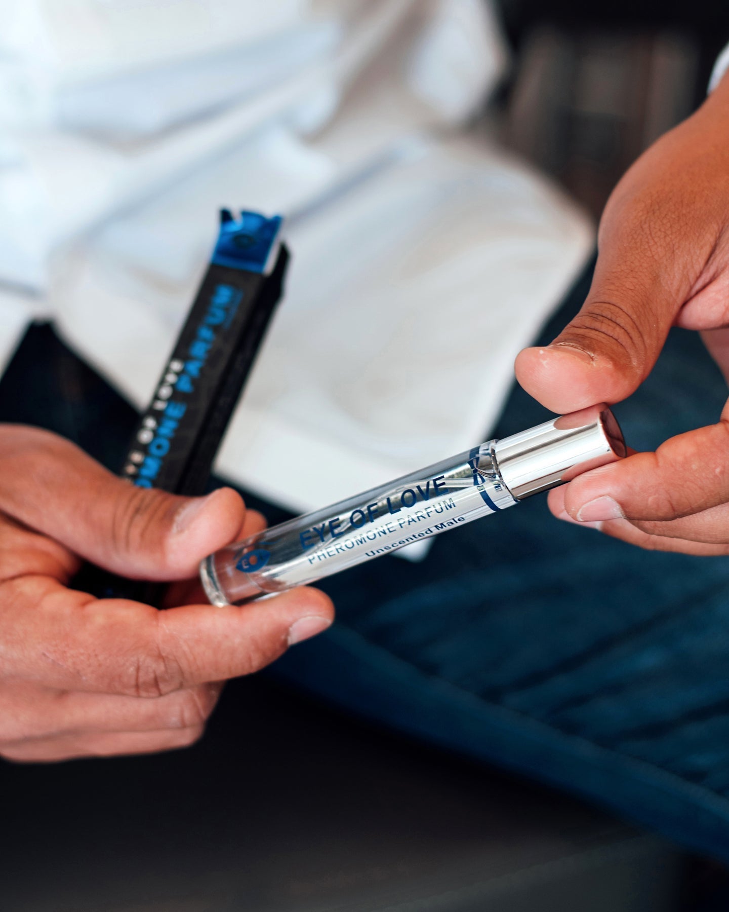 A man holds a rollerball bottle of Eye of Love unscented pheromone parfum for men.