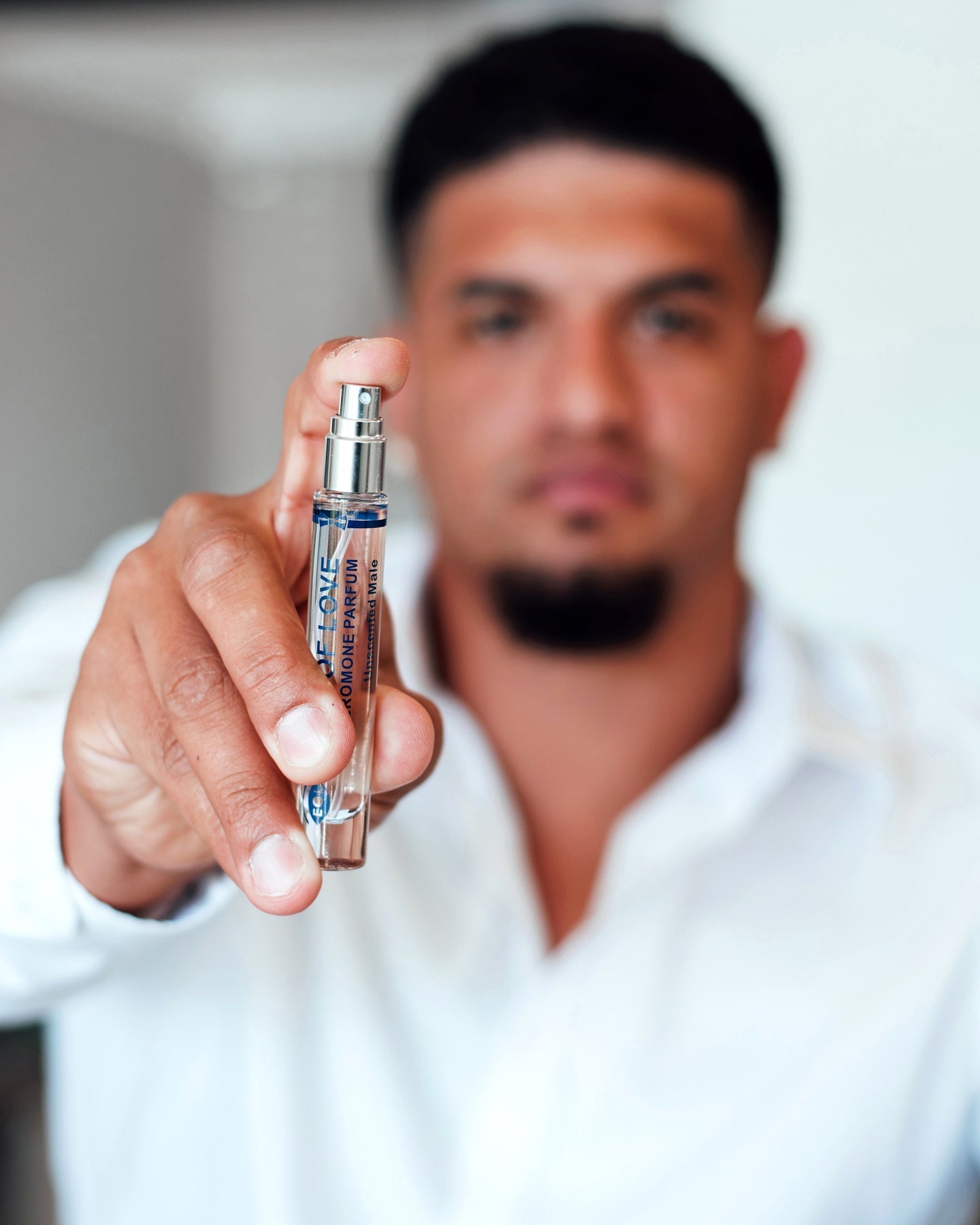 A man holds a small spray bottle of unscented pheromone oil.