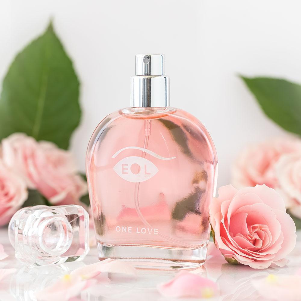 A pink perfume bottle with "EOL ONE LOVE" printed on it, surrounded by pink roses.
