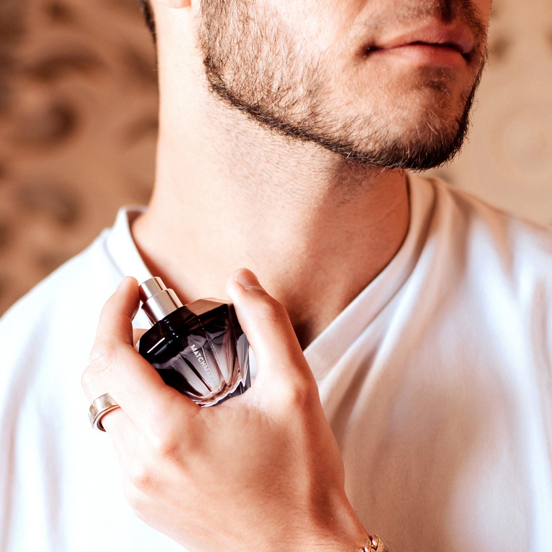 A man applies Black Diamond Pheromone Parfum for Men from a dark glass bottle.