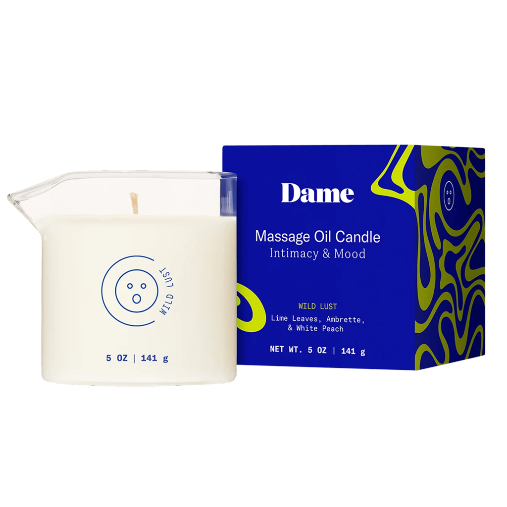 Wild Lust massage oil candle in a glass vessel next to its blue box.