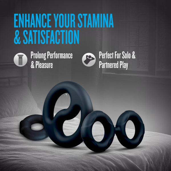 A 3-piece set of black silicone cock rings and a ball stretcher on a bed.