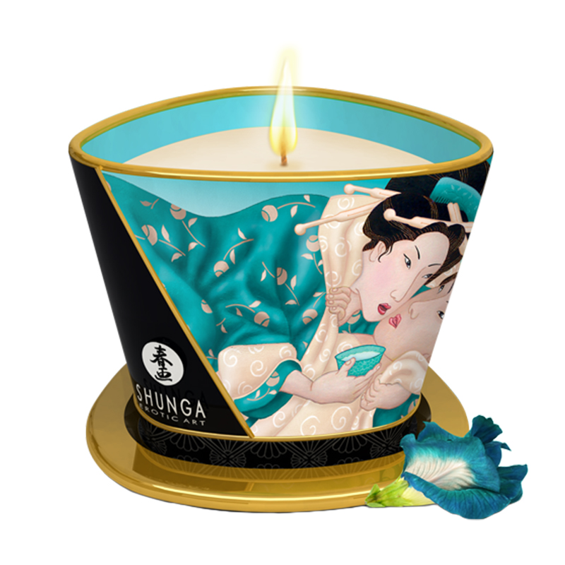A lit massage candle with a Japanese art motif and a blue flower.