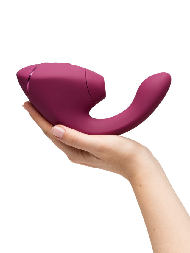 A dusky pink dual G-spot and clitoral stimulator held in a hand.