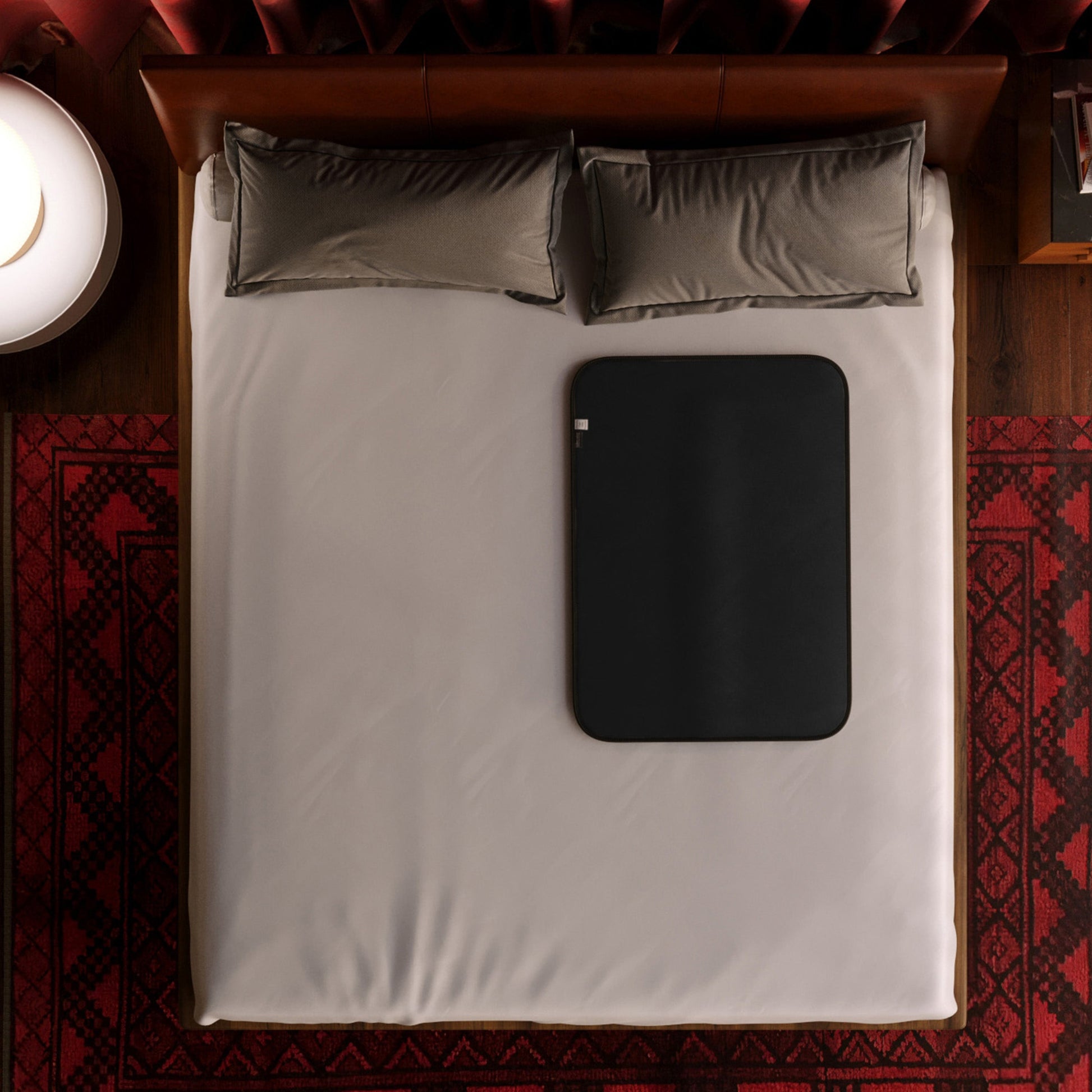 A black waterproof microvelvet throw blanket is placed on a bed.