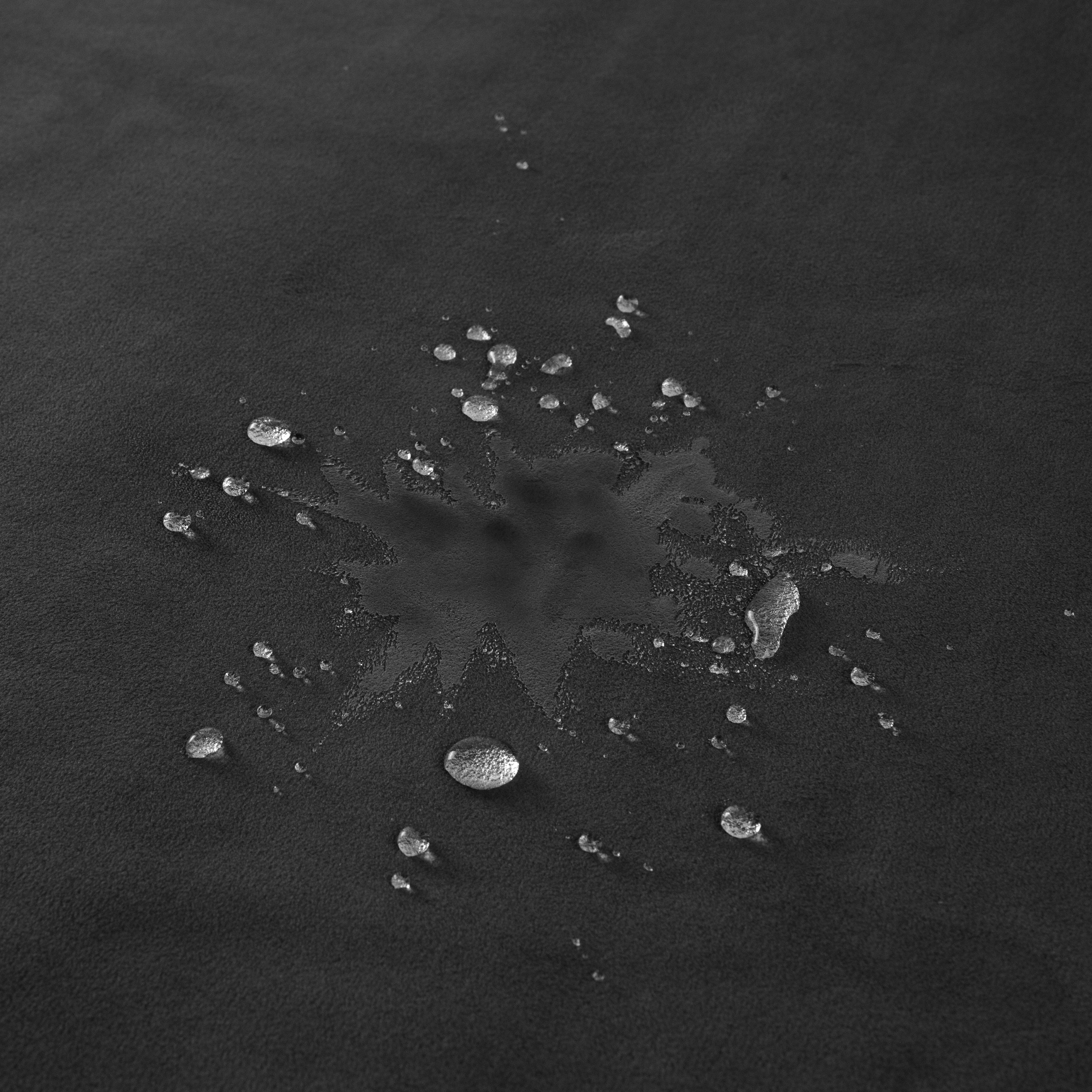 A black waterproof microvelvet throw blanket with water droplets on its surface.