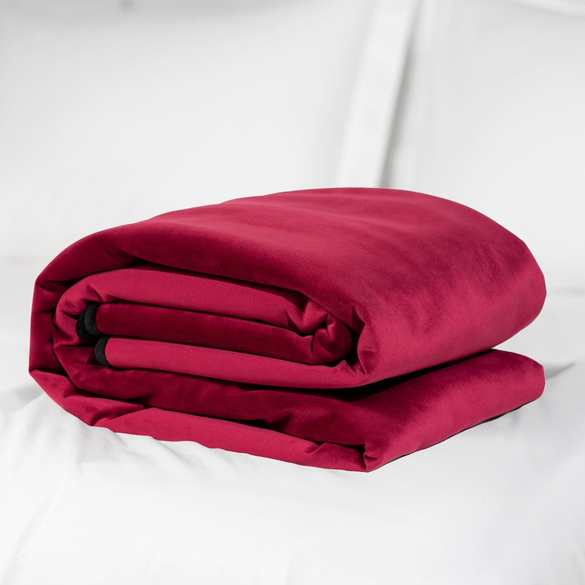 A folded, merlot-colored waterproof microvelvet throw on a white surface.