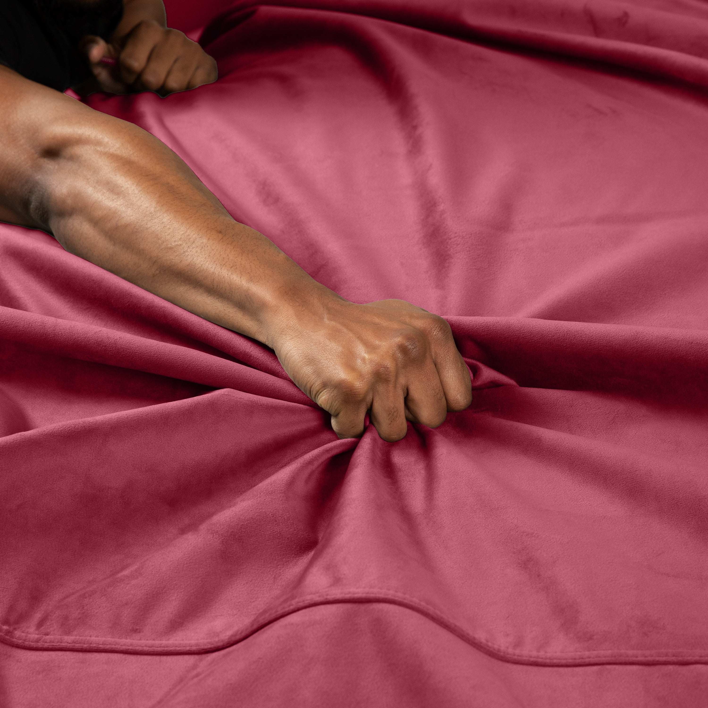 Waterproof microvelvet throw in mini merlot with a hand gripping the fabric.