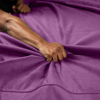 Aubergine microvelvet waterproof sex throw with a hand gripping the fabric.