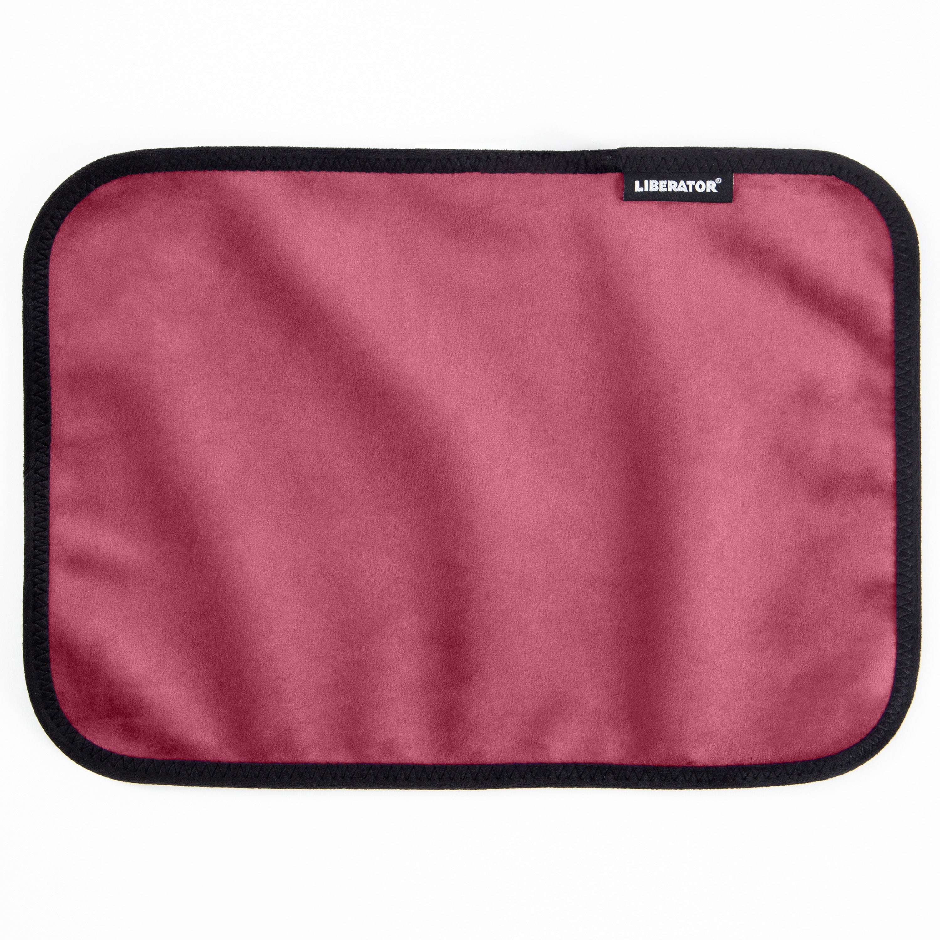 A rectangular pink microvelvet mat with a black stitched border and a Liberator logo.