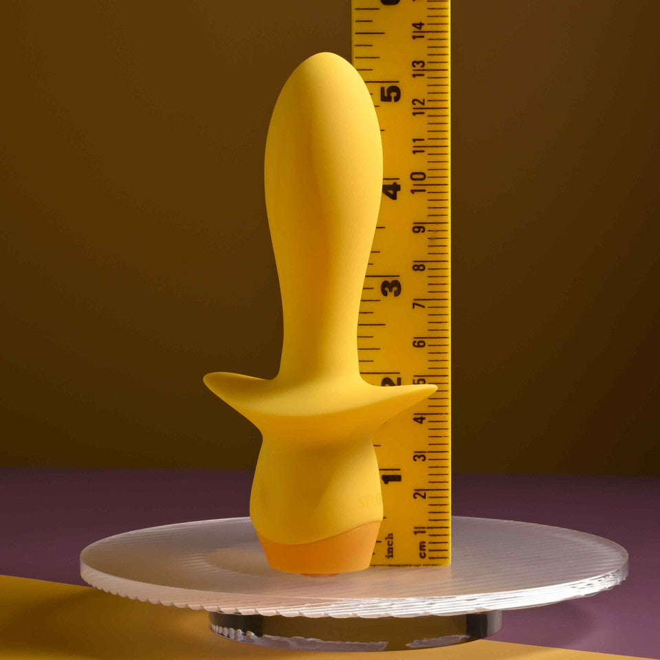 Yellow silicone vibrating plug with a ruler for scale.