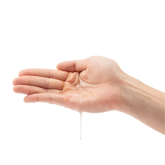 A hand holds a clear liquid lubricant that is dripping from the palm.