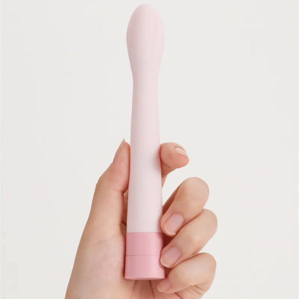 A hand holds a slim pink vibrator with a flexible tip.