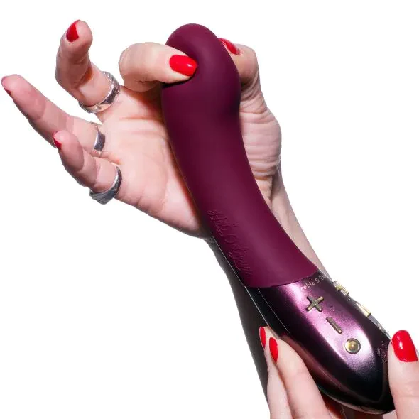 A burgundy Kurve G-spot vibrator with dual motors and control buttons held by hands with red nail polish.