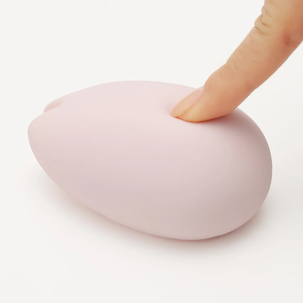 A pink silicone vibrator being pressed by a finger.