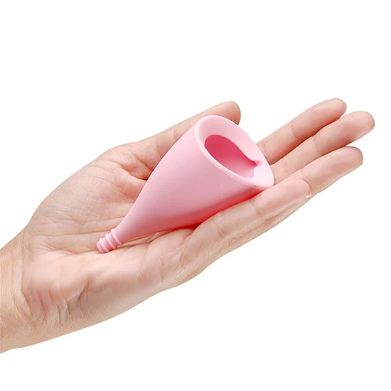 A pink menstrual cup with a stem rests in an open palm.