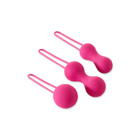 Three fuchsia silicone Kegel balls with retrieval loops on a white background.