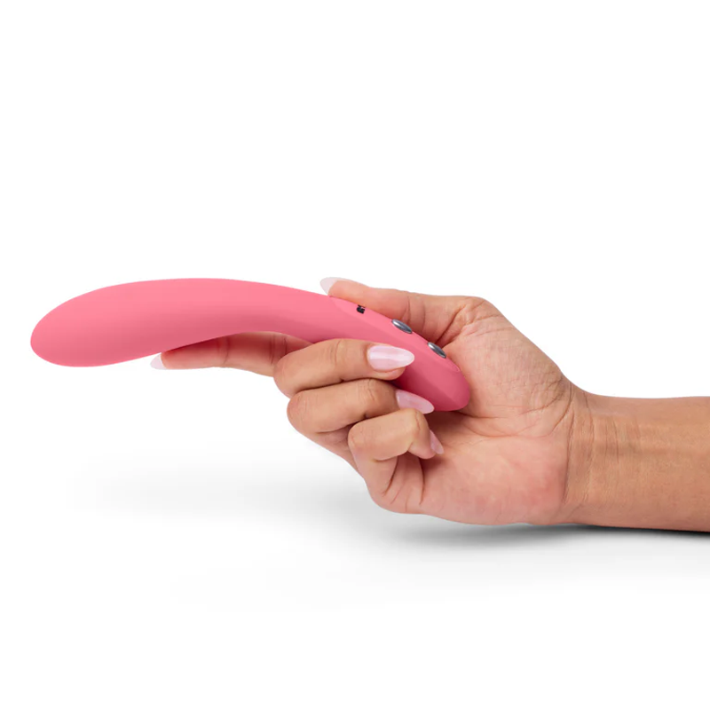 A hand holds a pink curved vibrator with buttons.