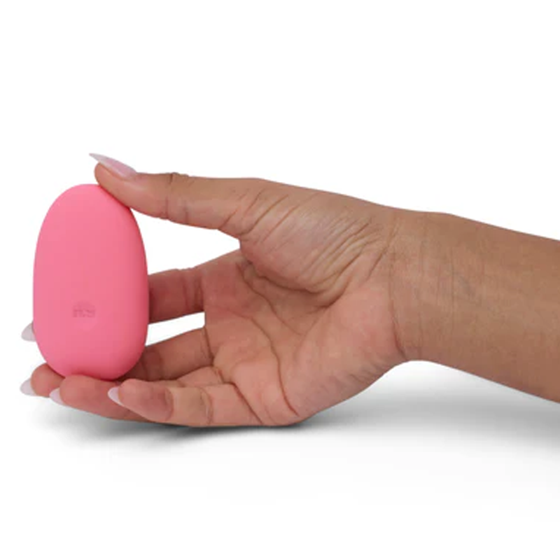 A hand holds a pink, pebble-shaped silicone clitoral vibrator.