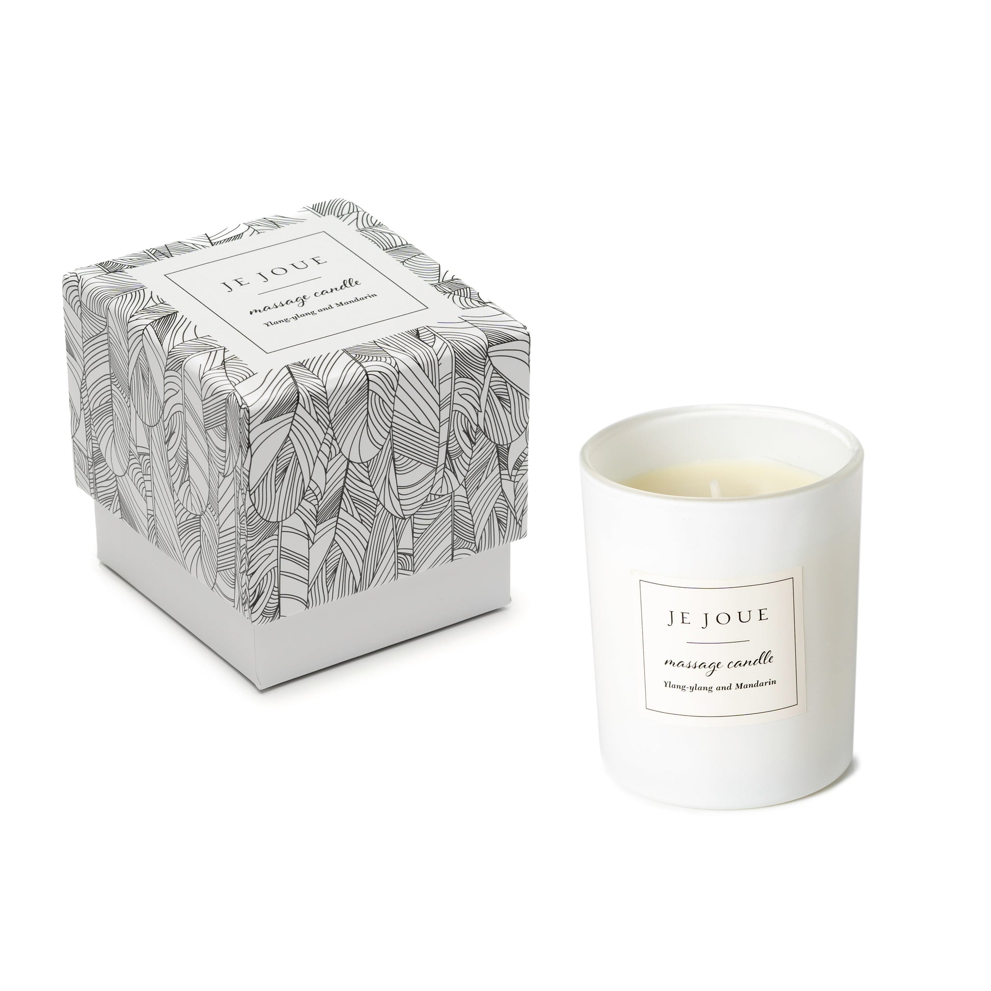 A Je Joue massage candle with Ylang Ylang and Mandarin scent in a white glass jar next to its patterned box.