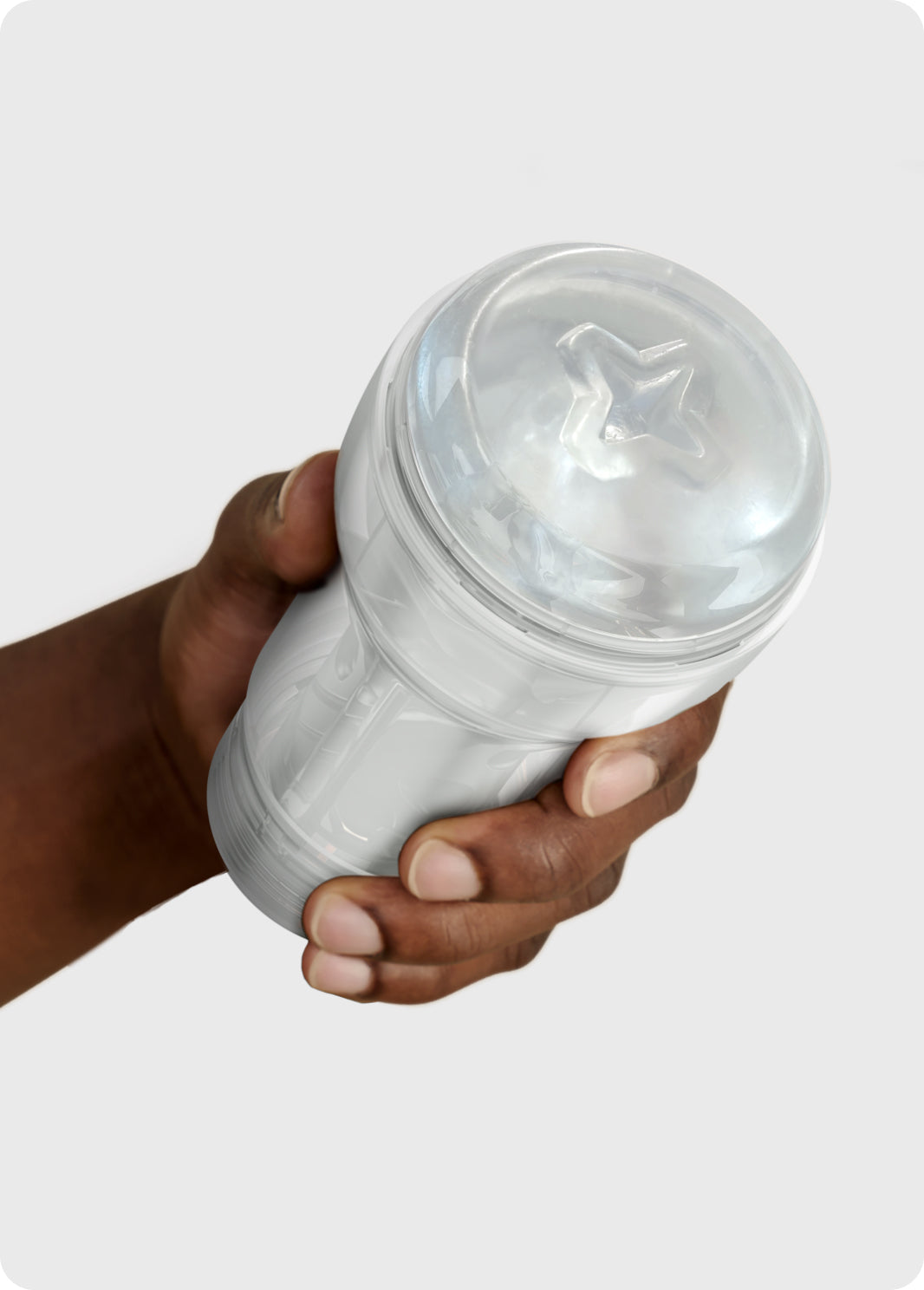 A hand holds a clear and white suction stroker with a star pattern inside.