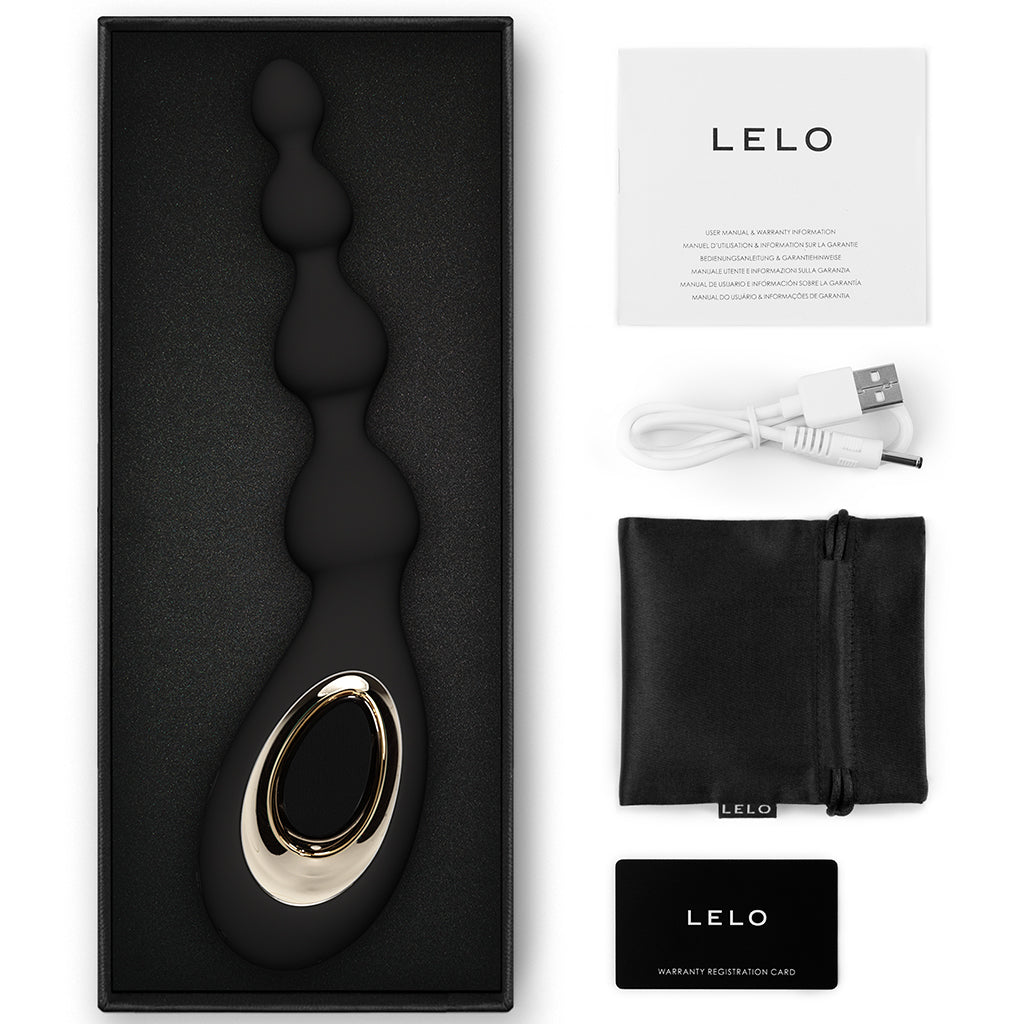 A black Lelo Soraya Beads anal massager with gold accents, charging cable, pouch, and warranty card.