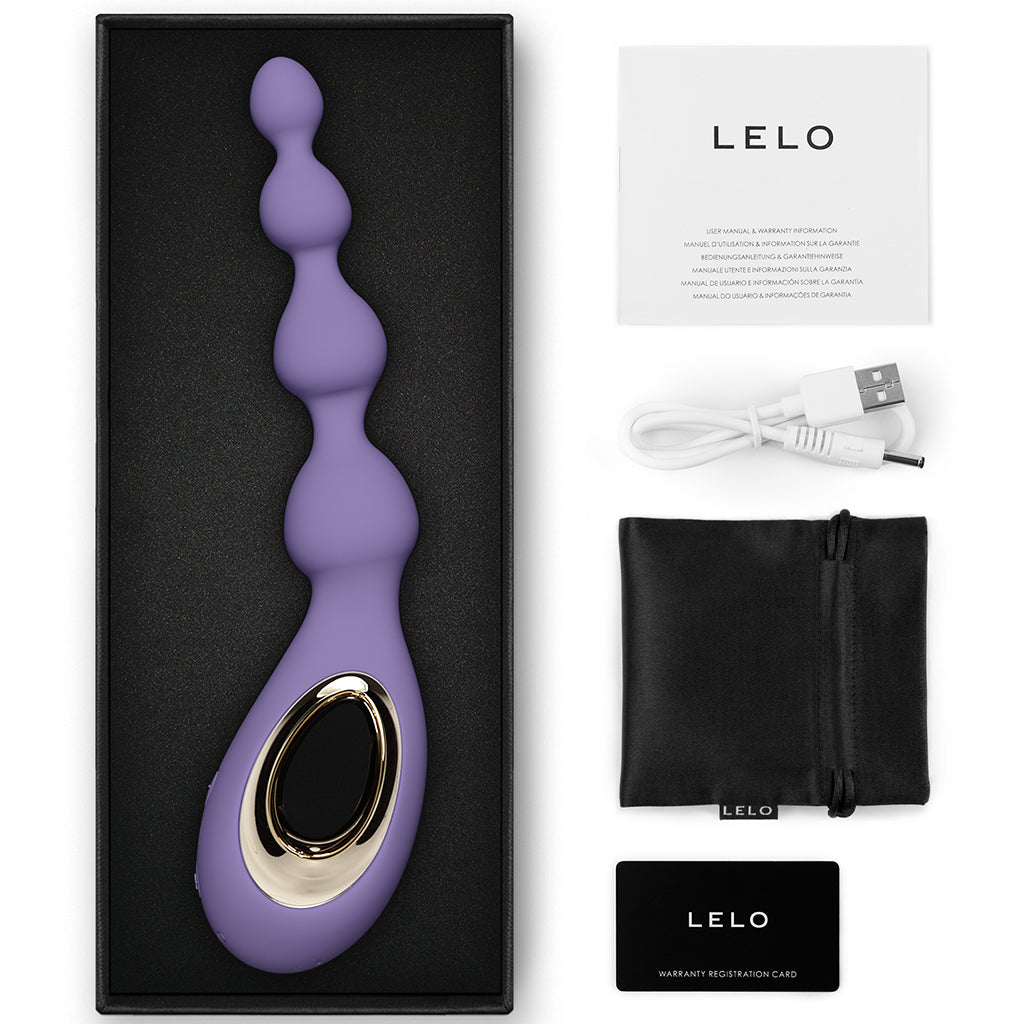 A purple silicone anal massager with gold accents, charging cable, pouch, and manual.