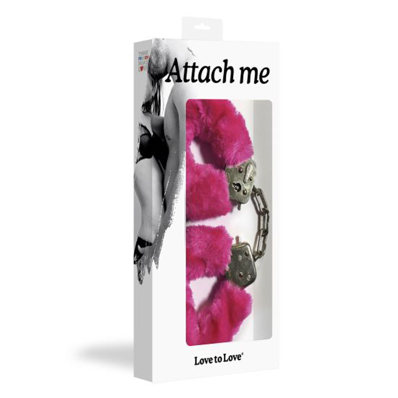 Pink faux fur lined metal handcuffs on a white box with "Attach me" text.