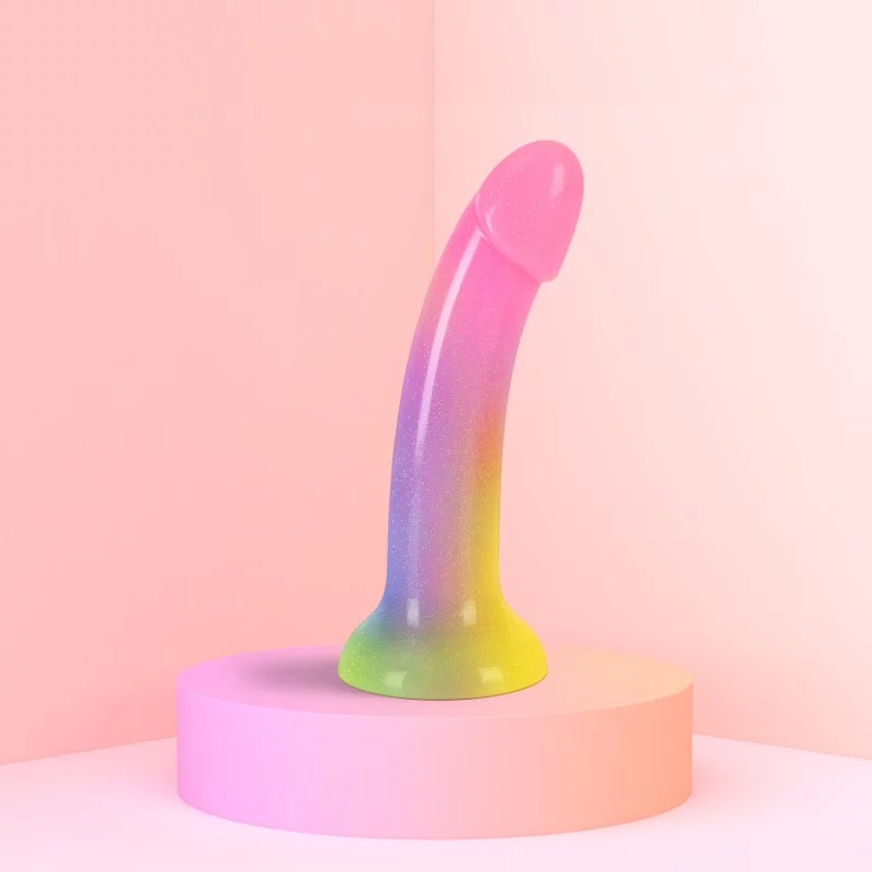 A rainbow glitter dildo with a suction cup base on a pink pedestal.