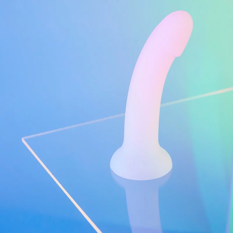 Curved pink silicone dildo with suction base on clear surface.