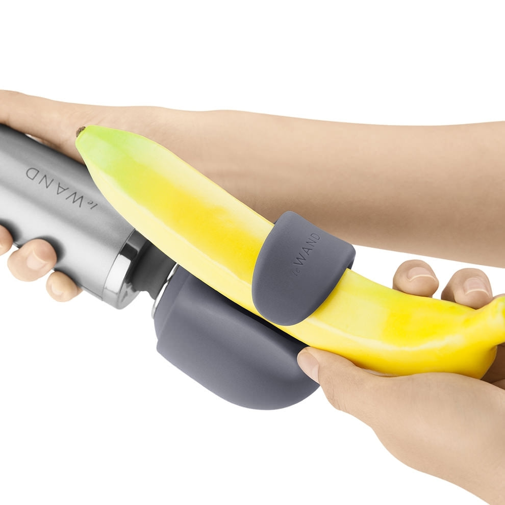 A grey silicone wand attachment is fitted around a banana.