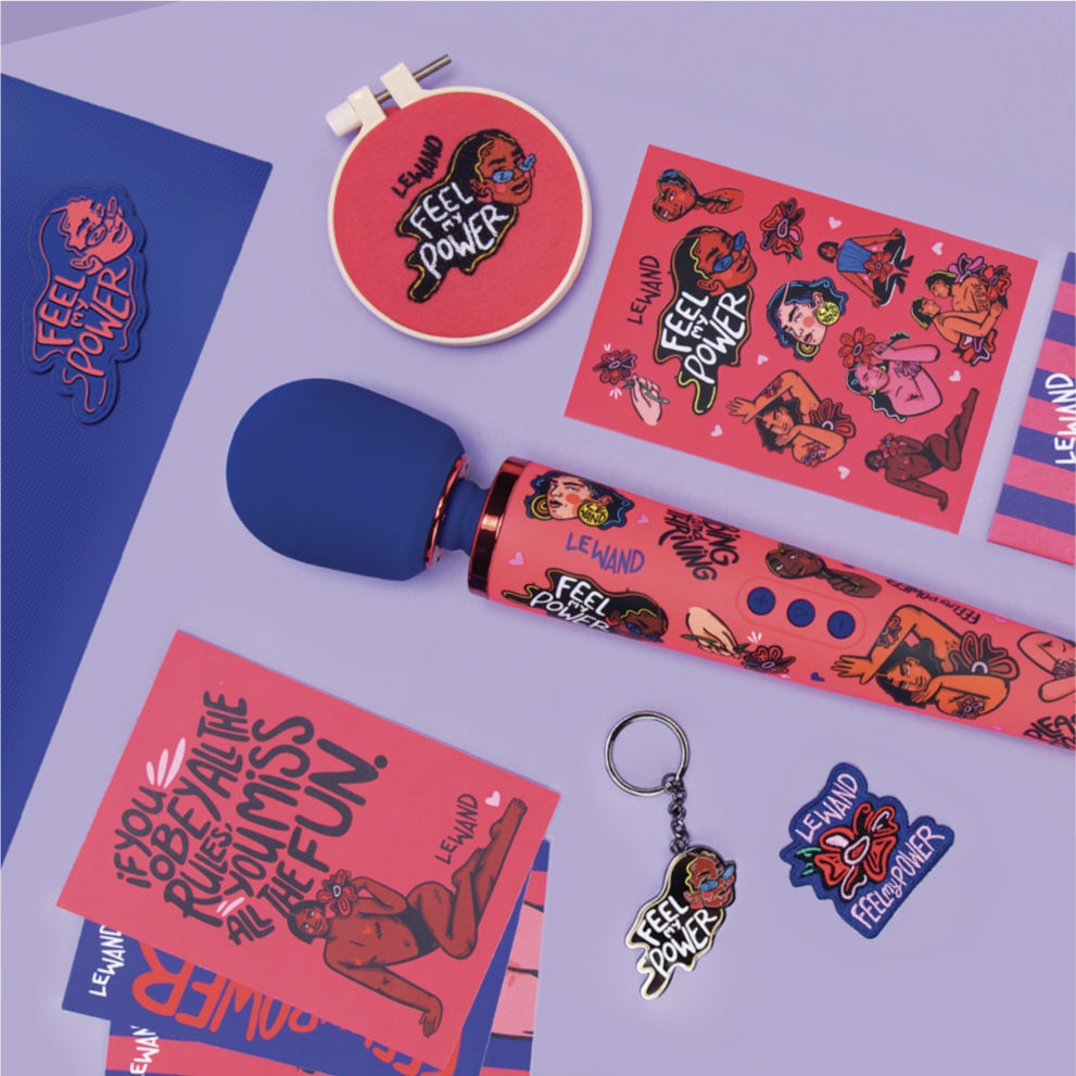 A blue and pink Le Wand vibrator with empowering artwork and accessories.