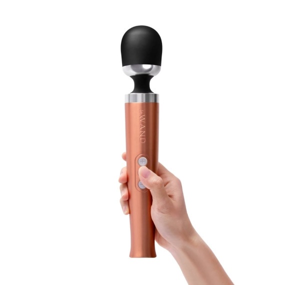 A hand holds a rose gold rechargeable wand massager with a black head.
