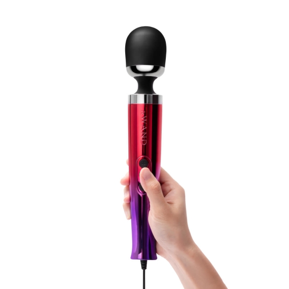 A hand holds a metallic red and purple wand massager with a black head.