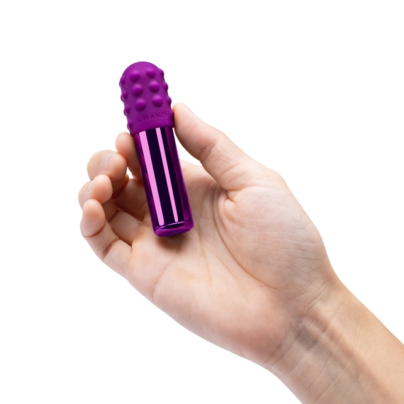 A purple bullet vibrator with a textured head held in a hand.