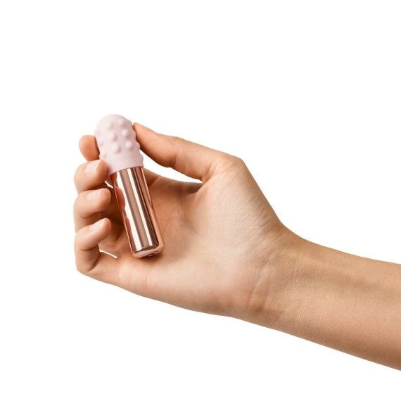 Rose gold bullet vibrator with a textured pink silicone tip held in a hand.