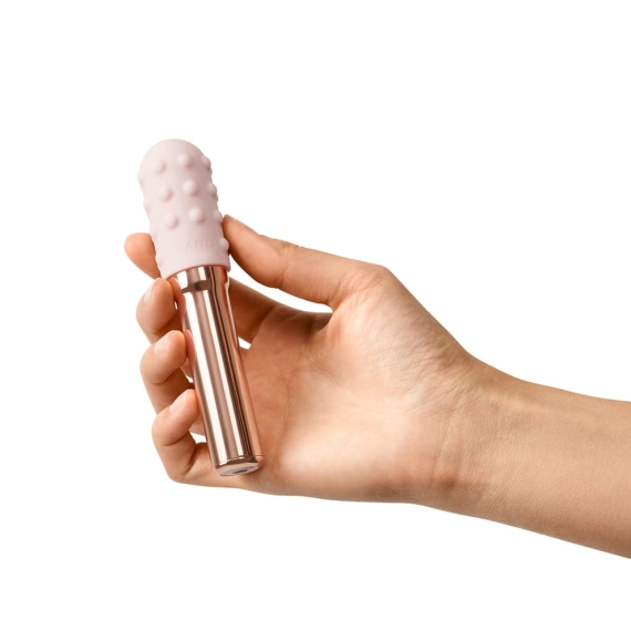 A rose gold vibrator with a textured pink silicone head held in a hand.