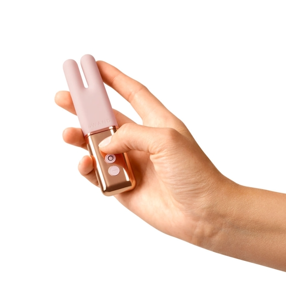 A hand holds a rose gold and pink mini vibe with two prongs.