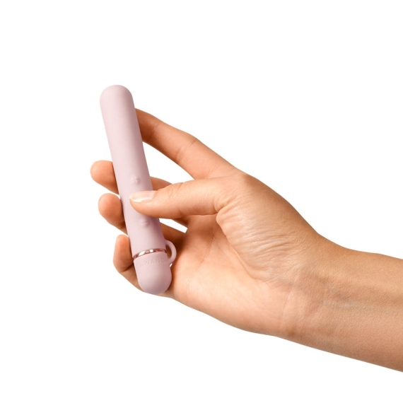 A hand holds a rose gold mini vibrator with a textured ring.