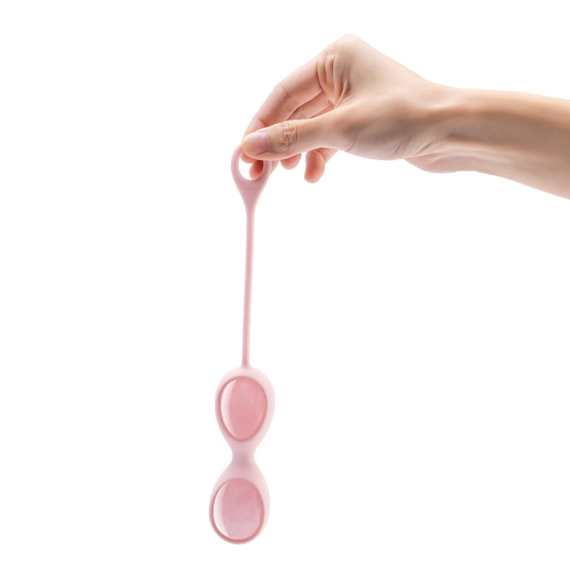 A hand holds a pink, double-egg shaped pelvic floor exerciser.