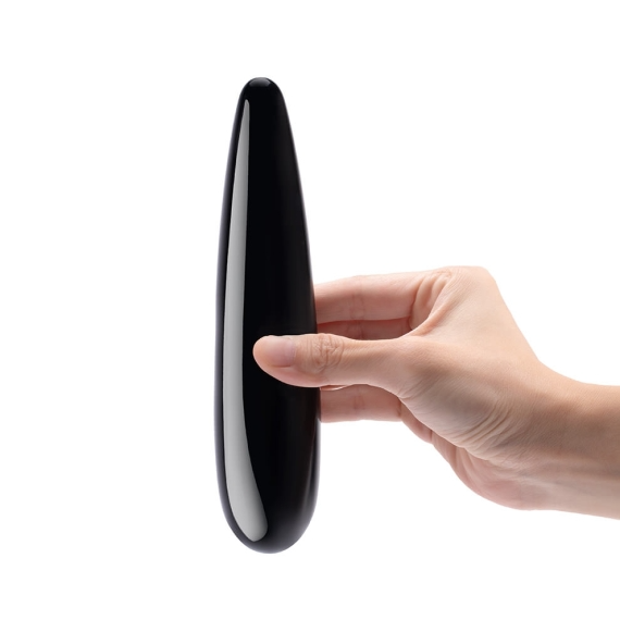 A hand holds a smooth, black obsidian crystal wand.