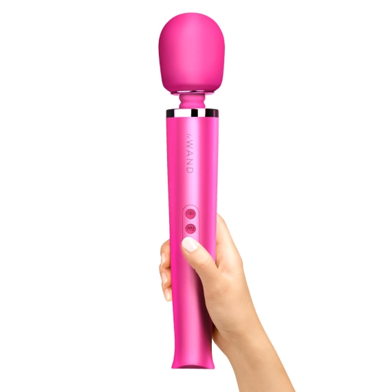 A pink rechargeable wand massager held in a hand.