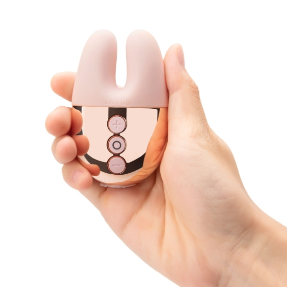 A rose gold and pink rabbit vibrator with three control buttons held in a hand.