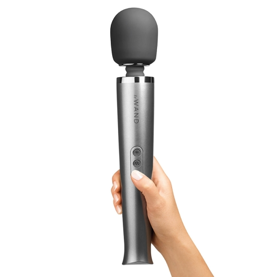A hand holds a gray rechargeable wand massager with a gray head and two buttons.