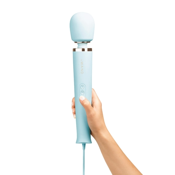 A hand holds a light blue plug-in wand massager with a silicone head.