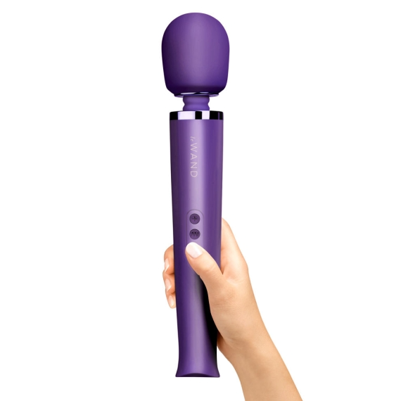 A purple rechargeable wand massager held in a hand.