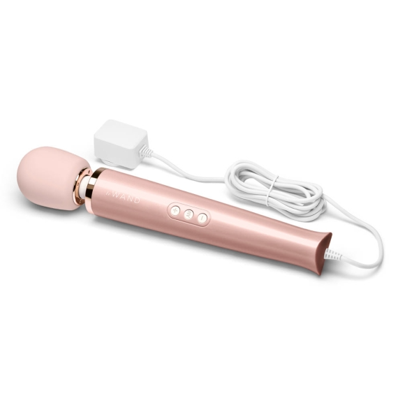 A rose gold plug-in wand massager with a white cord and charger.