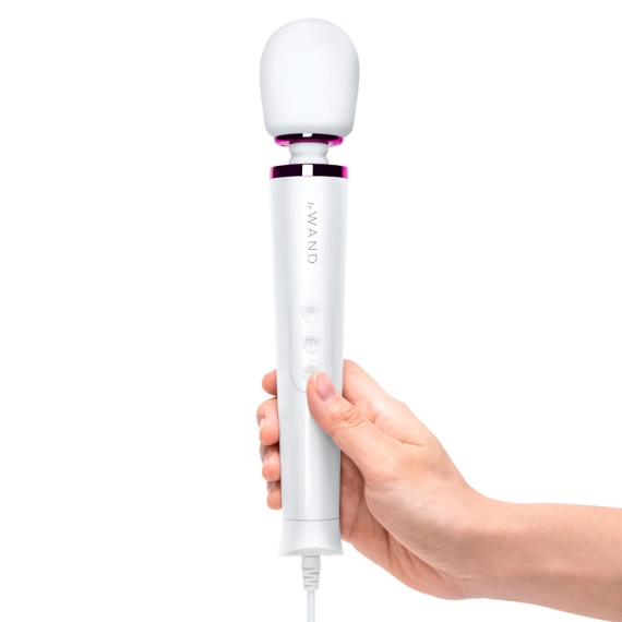 A white wand massager with a pink band is held in a hand.